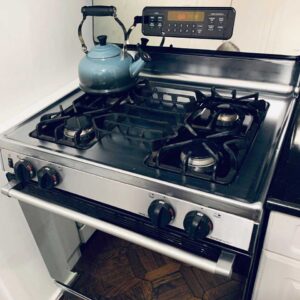 A stainless steel stovetop with a silver kettle on top.